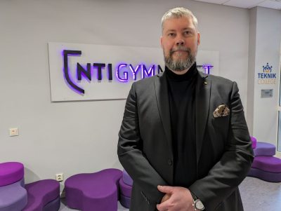 Rektor Anders Tegerhult på NTI Västerås står framför NTI:s logga på väggen.