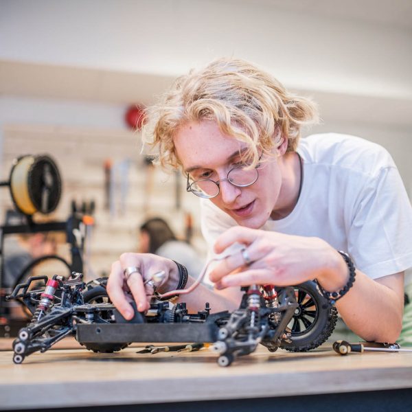 En elev på teknikprogrammet meckar med en robot i makerspace