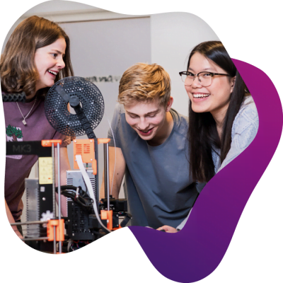 3 elever står runt en 3D-printer i makerspace och pratar och skrattar med varandra