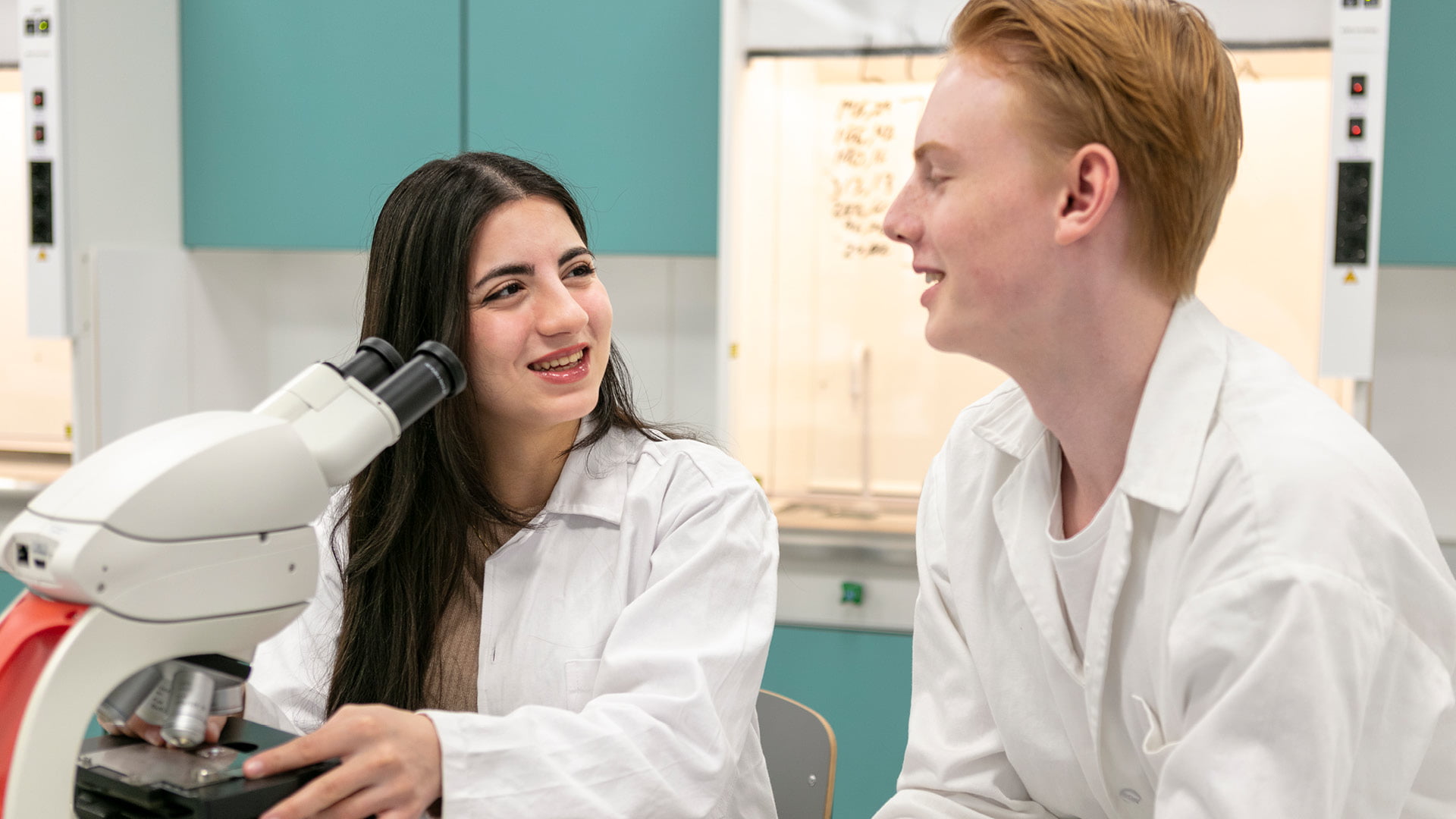 Två glada elever arbetar i labbsalen