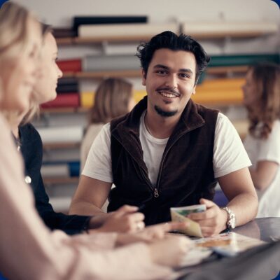 Glad elev som pratar med andra klasskompisar under lektionen och tittar in i kameran.
