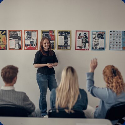 En glad elev som håller i en redovisning framför sina klasskamrater.