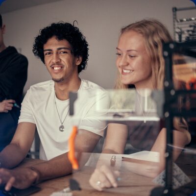 Glada elever i Makerspace vid 3D-printer som tittar på datorn.